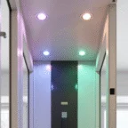 A modern hallway ceiling with four recessed lights emitting different colors: purple, orange, blue, and green.