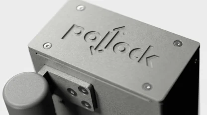 Close-up of a gray metal device featuring the engraved word "Pollock" on its surface, with a cylindrical component attached to the side.