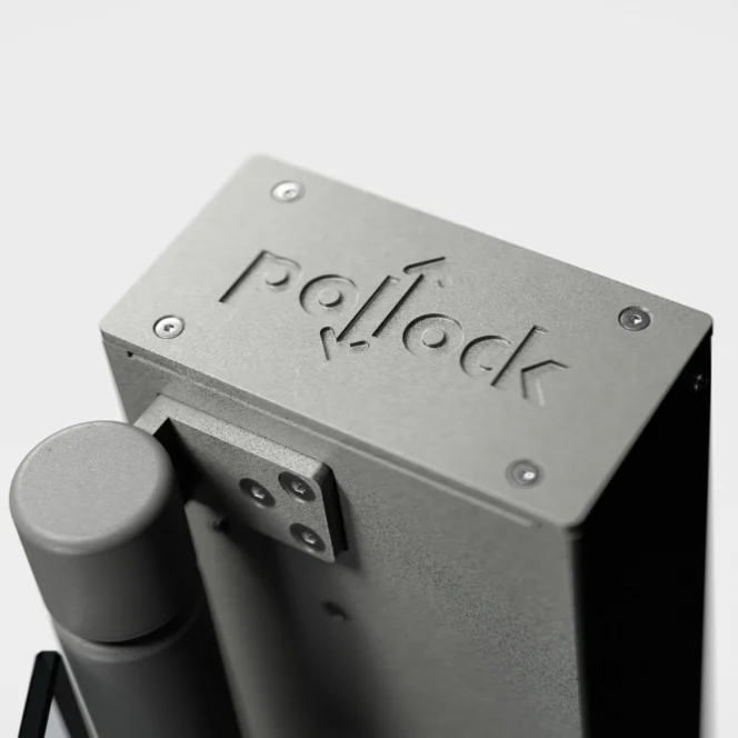 Close-up of a gray metal device featuring the engraved word "Pollock" on its surface, with a cylindrical component attached to the side.