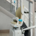 A motorized stair lift with a beige seat is installed along a curved staircase in a modern home interior.