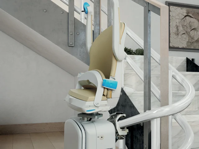 A motorized stair lift with a beige seat is installed along a curved staircase in a modern home interior.