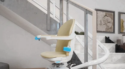 A motorized stairlift with a beige seat is installed on a curved railing along a modern indoor staircase.