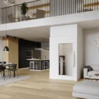 Modern open-plan living area with a small residential elevator, dining table, kitchen, and staircase leading to an upper loft. Minimalist decor and neutral color palette.