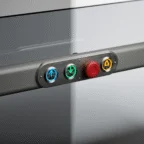 A control panel with blue up, green down, red emergency stop, and yellow automatic buttons mounted on a metallic surface.