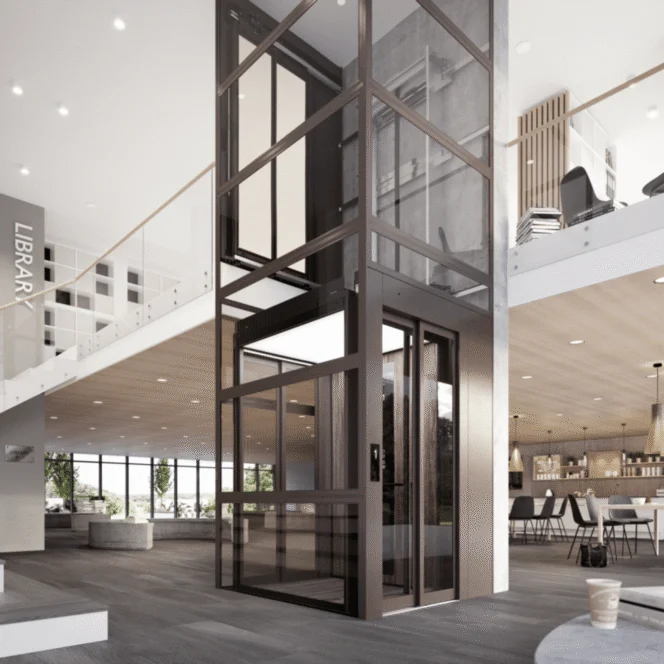 Modern glass elevator in a spacious, contemporary building lobby with a library sign visible and open seating areas on both floors.
