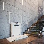 A stairlift platform for wheelchair access is installed beside a modern staircase with a metal railing and illuminated steps.