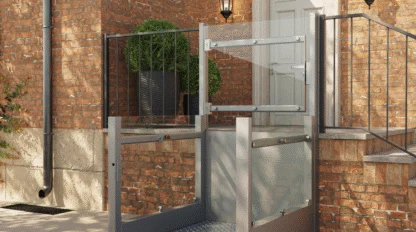 A metal wheelchair lift is installed beside outdoor stairs, providing accessible entry to a brick building with a white door and black railings.